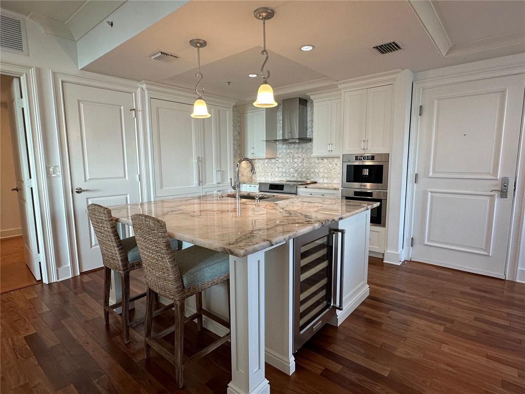 1350 Main Street, Unit 1401 Sarasota, FL 34236 - Photo 13 of 69 a kitchen with kitchen island a wooden floor and white appliances