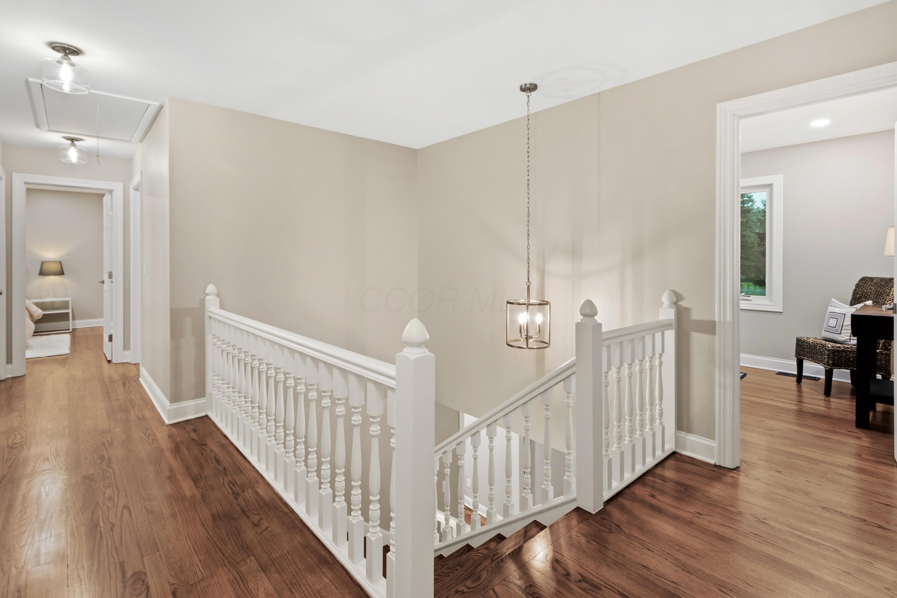 1560 Carriage Road Powell, OH 43065 - Photo 33 of 73 Wood-finish flooring throughout, white painted balusters and newel posts, and a decorative pendant light fixture