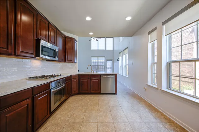 a kitchen with stainless steel appliances a sink a stove a microwave a sink a refrigerator and cabinets