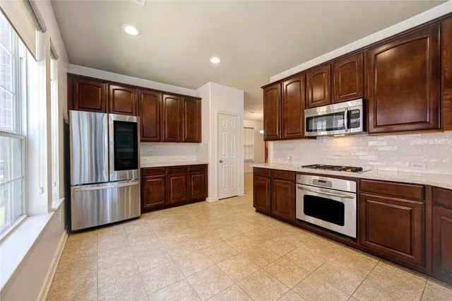 a view of kitchen with kitchen island granite countertop stainless steel appliances refrigerator sink microwave and cabinets
