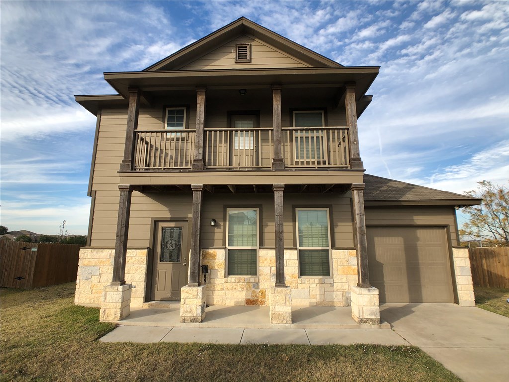 View of front of home with a porch, concrete driveway, a garage, and stone siding