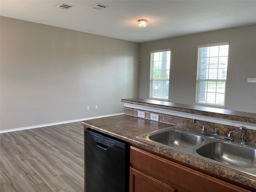 304 Azurite Drive Jarrell, TX 76537 - Photo 9 of 24 Kitchen featuring dark countertops, dishwasher, light wood-type flooring, and brown cabinets