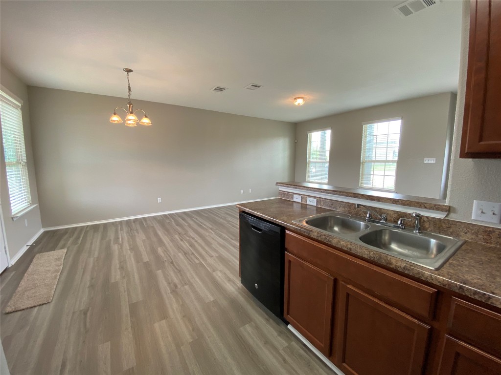 304 Azurite Drive Jarrell, TX 76537 - Photo 21 of 24 Kitchen featuring a peninsula, dark countertops, dishwasher, light wood-type flooring, and decorative light fixtures