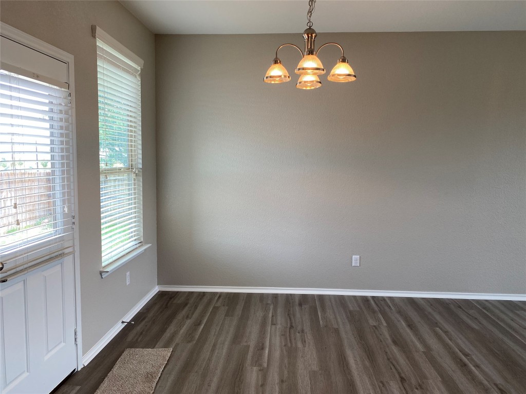304 Azurite Drive Jarrell, TX 76537 - Photo 7 of 24 Unfurnished dining area featuring dark wood-type flooring and a chandelier