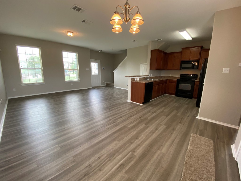 304 Azurite Drive Jarrell, TX 76537 - Photo 23 of 24 Kitchen featuring open floor plan, brown cabinetry, a peninsula, black appliances, and hanging light fixtures