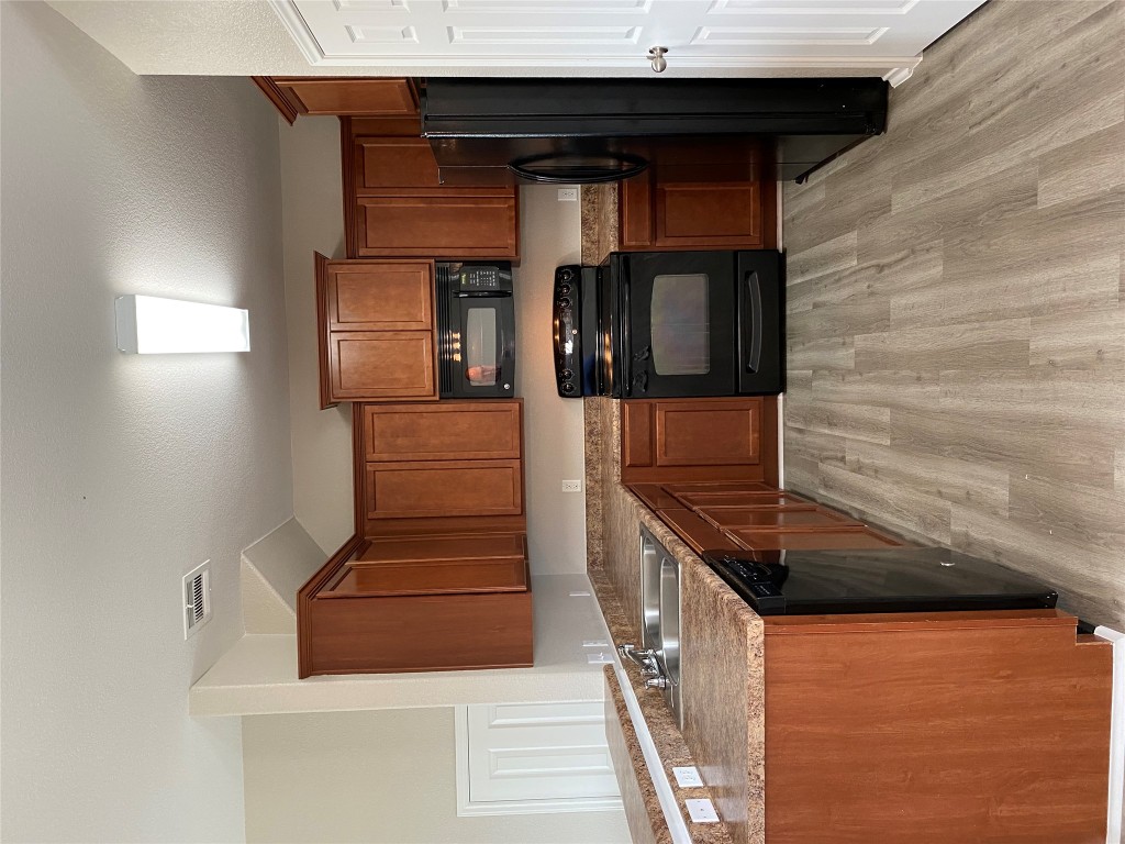 304 Azurite Drive Jarrell, TX 76537 - Photo 8 of 24 Kitchen featuring black appliances, brown cabinetry, light wood-style floors, and a peninsula
