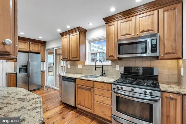 a kitchen with stainless steel appliances granite countertop a stove sink microwave and refrigerator