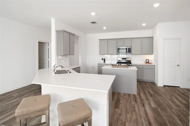 a kitchen with a sink a stove a refrigerator and white cabinets with wooden floor