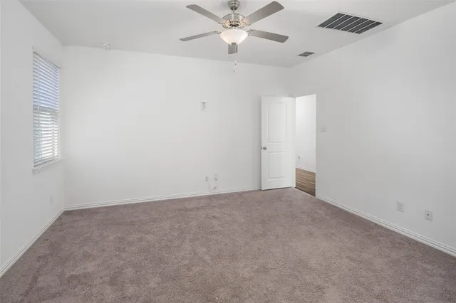 an empty room with a window and a fan