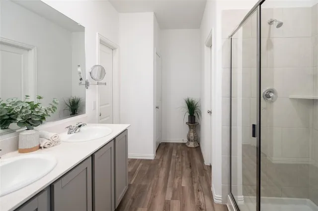 a bathroom with a sink a mirror a potted plant and a shower