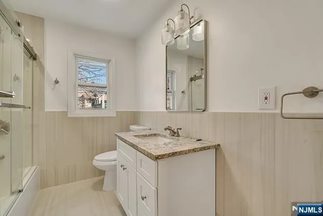 a bathroom with a granite countertop sink a toilet and a mirror