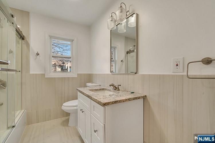 13 Casta Lane, Unit 1 Edgewater, NJ 07020 - Photo 12 of 25 a bathroom with a granite countertop sink a toilet and a mirror