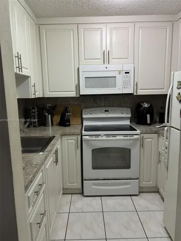 a kitchen with white cabinets and appliances