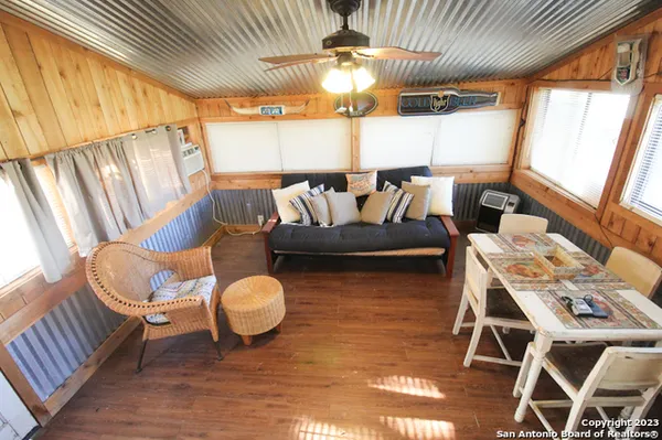a living room with couches chairs and a dining table with wooden floor