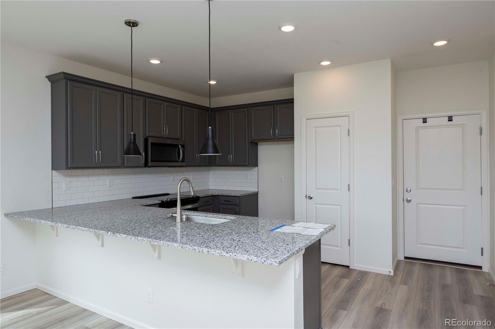313 Rodden Drive Erie, CO 80516 - Photo 11 of 25 a kitchen with kitchen island granite countertop a sink a counter space appliances and cabinets