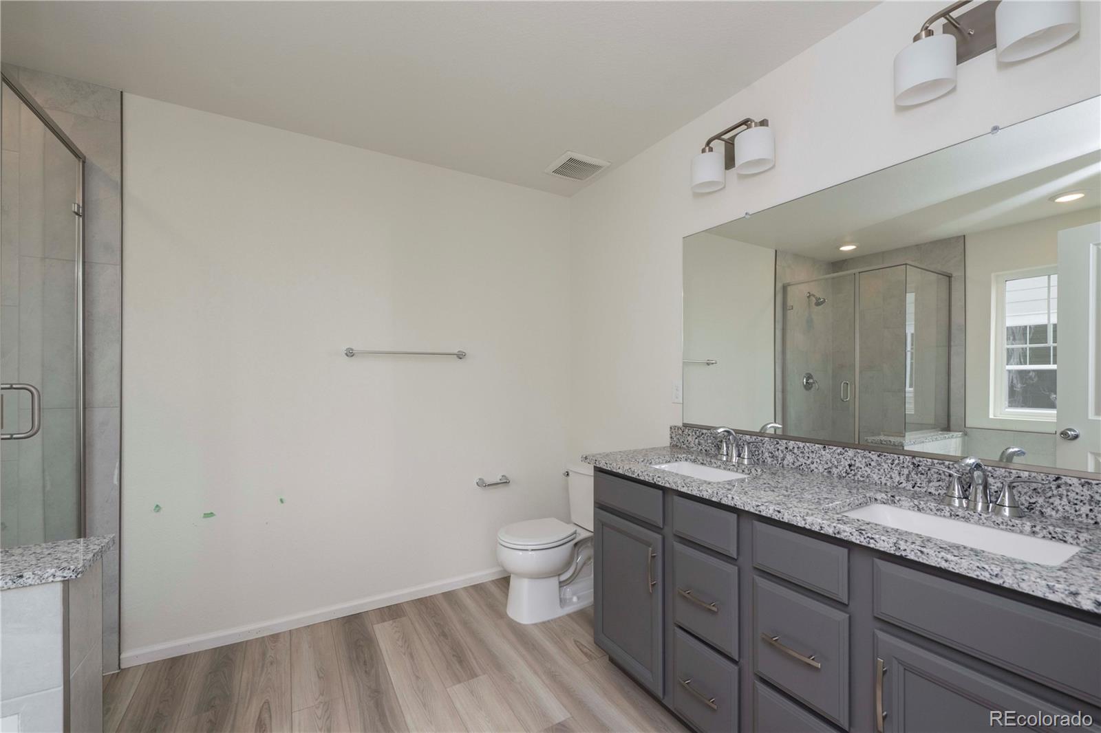 313 Rodden Drive Erie, CO 80516 - Photo 17 of 25 a bathroom with a granite countertop sink a toilet and a large mirror