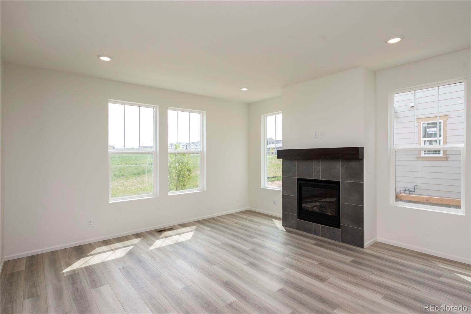 313 Rodden Drive Erie, CO 80516 - Photo 5 of 25 an empty room with wooden floor fireplace and windows