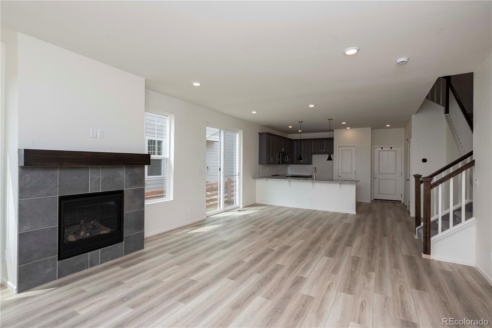 313 Rodden Drive Erie, CO 80516 - Photo 7 of 25 a view of kitchen and empty room with wooden floor and a fireplace