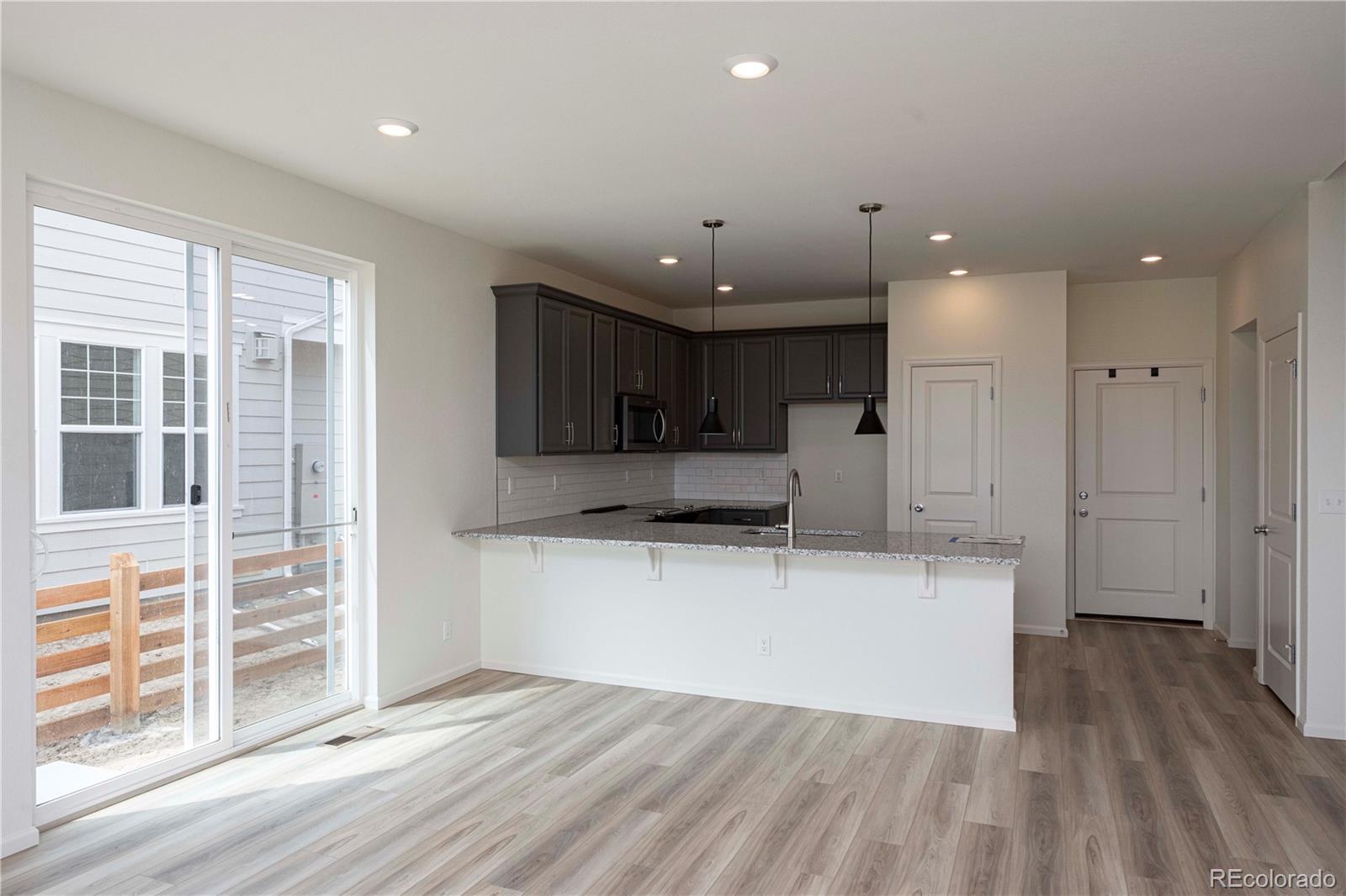 313 Rodden Drive Erie, CO 80516 - Photo 9 of 25 a large kitchen with stainless steel appliances kitchen island a large counter top and a wooden floors