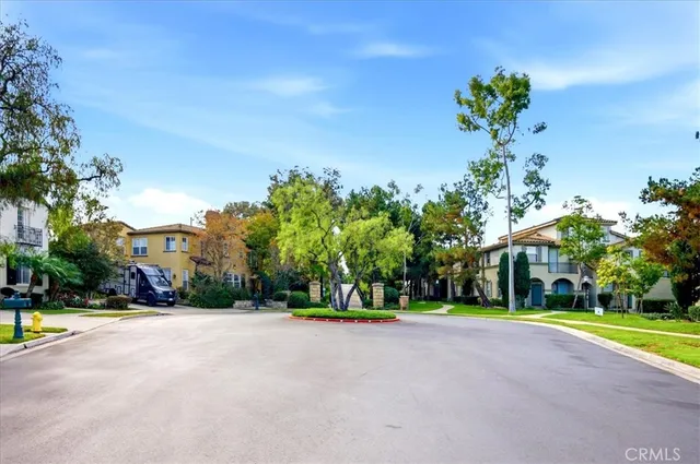 a view of a house with a yard plants and large tree