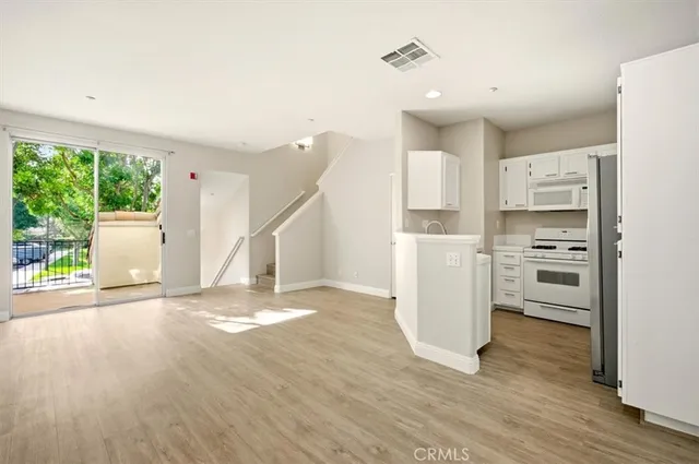 a view of a kitchen with wooden floor and electronic appliances