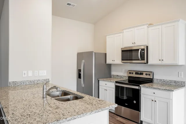 a kitchen with granite countertop a sink stove and refrigerator