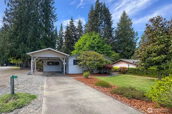 a view of a house with a yard and large tree