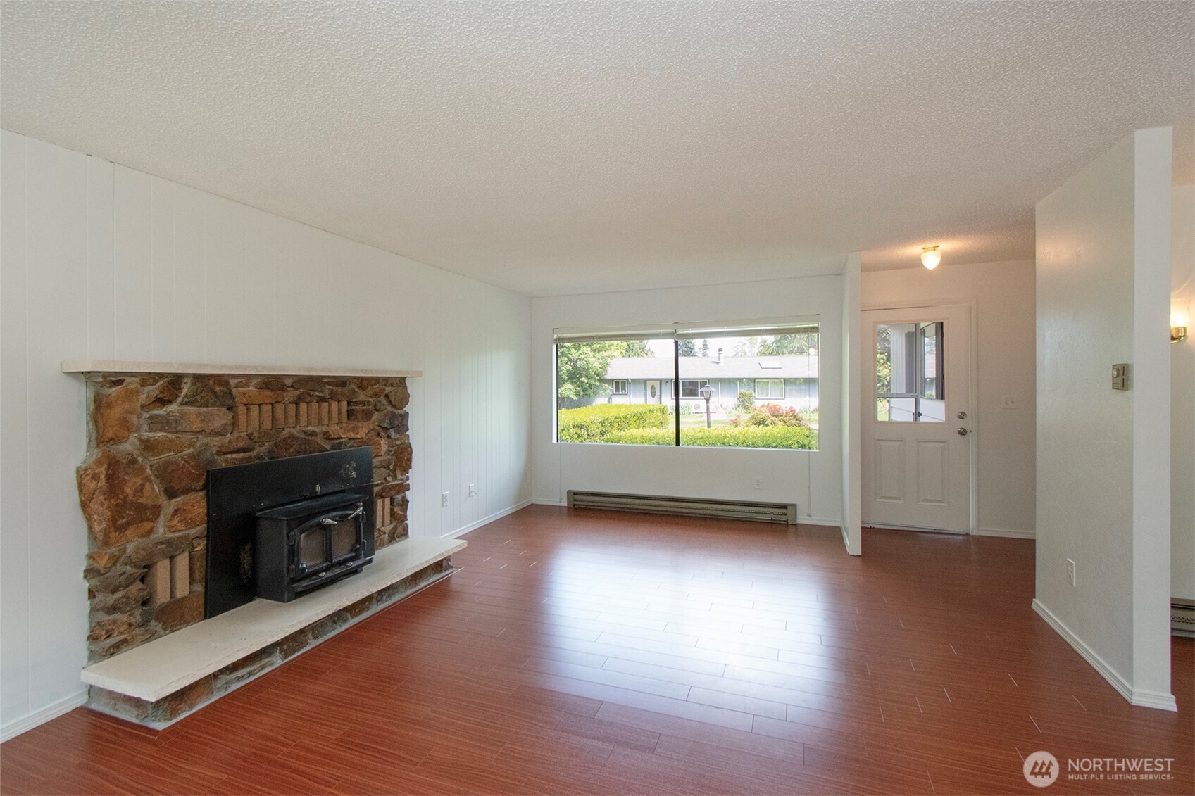 370 Dungeness Meadows Sequim, WA 98382 - Photo 7 of 40 an empty room with wooden floor fireplace and windows