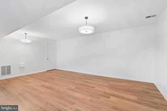 a view of an empty room with wooden floor and windows