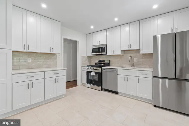 a kitchen with granite countertop white cabinets and stainless steel appliances