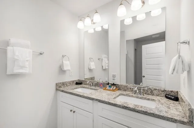 a bathroom with a granite countertop double vanity sink and a mirror