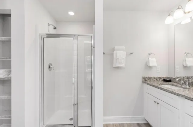 a bathroom with a granite countertop sink a mirror and shower