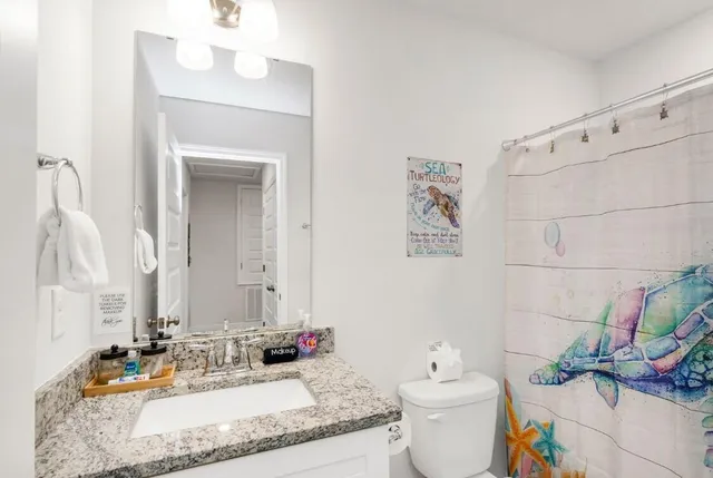 a bathroom with a granite countertop sink a toilet and a mirror