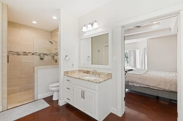a en suite bathroom with a granite countertop sink mirror and toilet