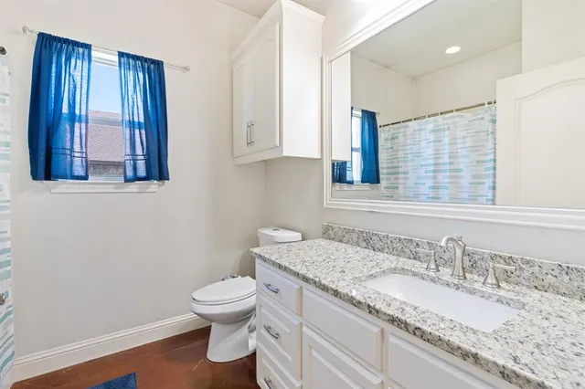 a bathroom with a granite countertop toilet sink and mirror