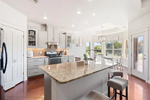 a kitchen with granite countertop kitchen island stainless steel appliances a sink and a refrigerator