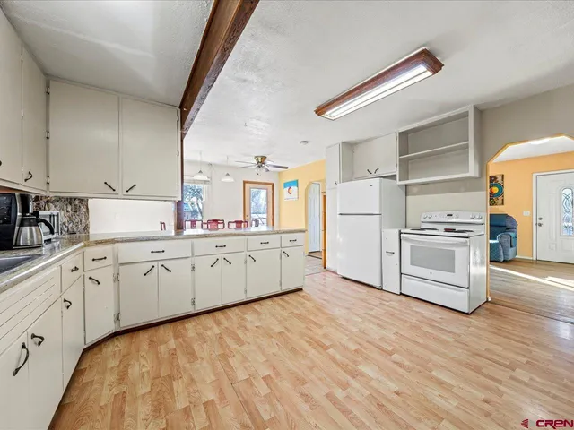 a kitchen with granite countertop white cabinets and white appliances