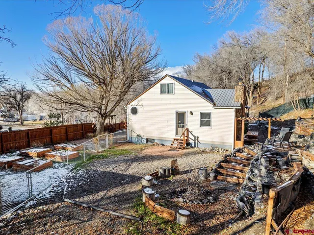 a view of a white house next to a yard with wooden fence