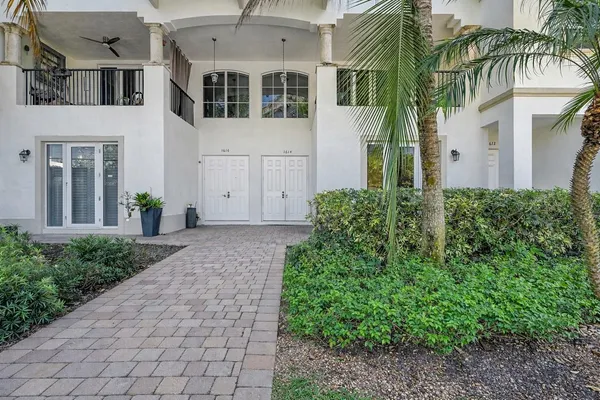a view of a white house with a plants and a pathway