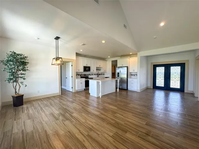 an empty room with wooden floor chandelier and glass door