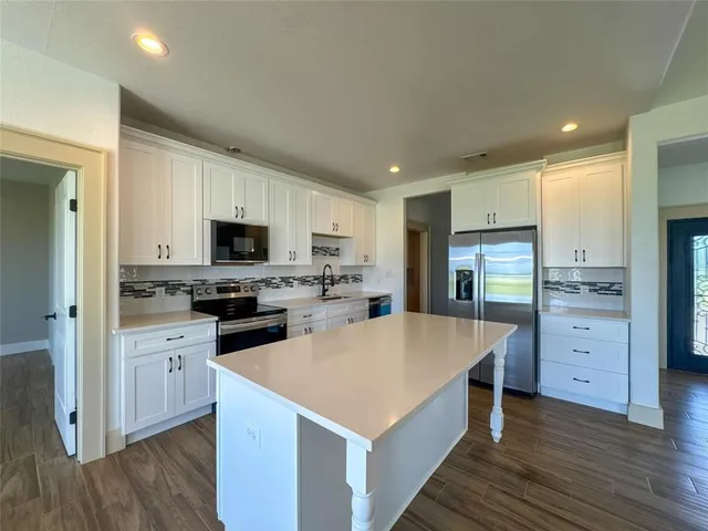 a kitchen with stainless steel appliances kitchen island granite countertop a stove top oven a sink dishwasher and a microwave oven with wooden floor