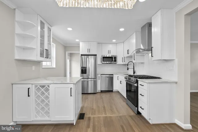 a kitchen with stainless steel appliances a stove a sink and white cabinets