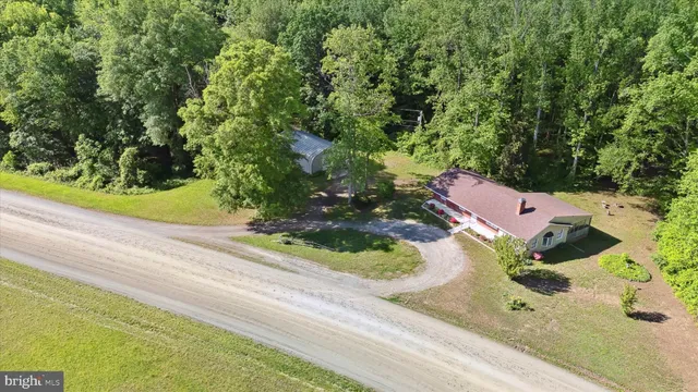 an aerial view of a house with a yard and trees all around