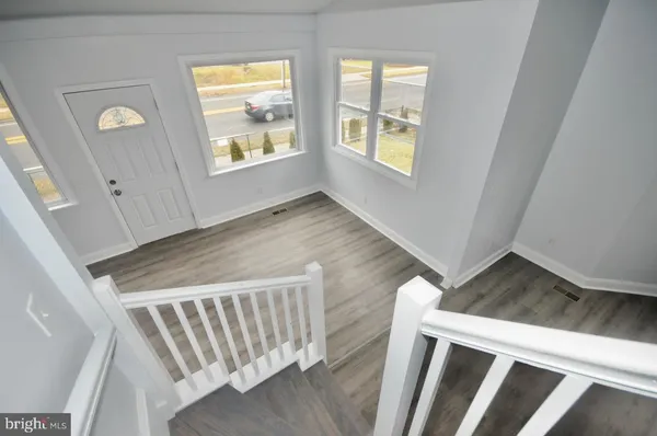 a view of an empty room with wooden floor and windows