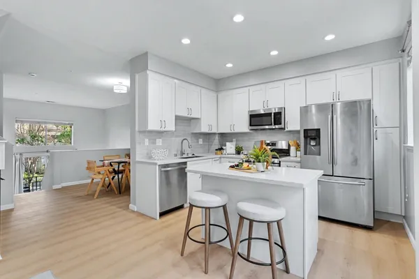 a kitchen with a refrigerator a microwave a stove a dining table and chairs