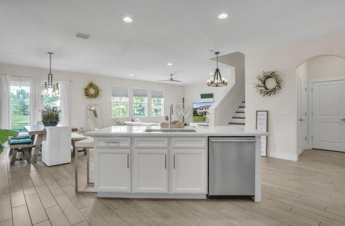 11971 Cypress Key Way Royal Palm Beach, FL 33411 - Photo 3 of 19 a kitchen with a sink dishwasher a dining table and chairs with wooden floor