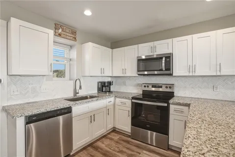 a kitchen with granite countertop white cabinets and stainless steel appliances