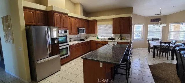 a kitchen with stainless steel appliances granite countertop a refrigerator a stove a sink a dining table and chairs