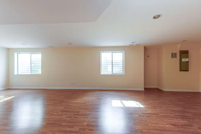 an empty room with wooden floor and windows