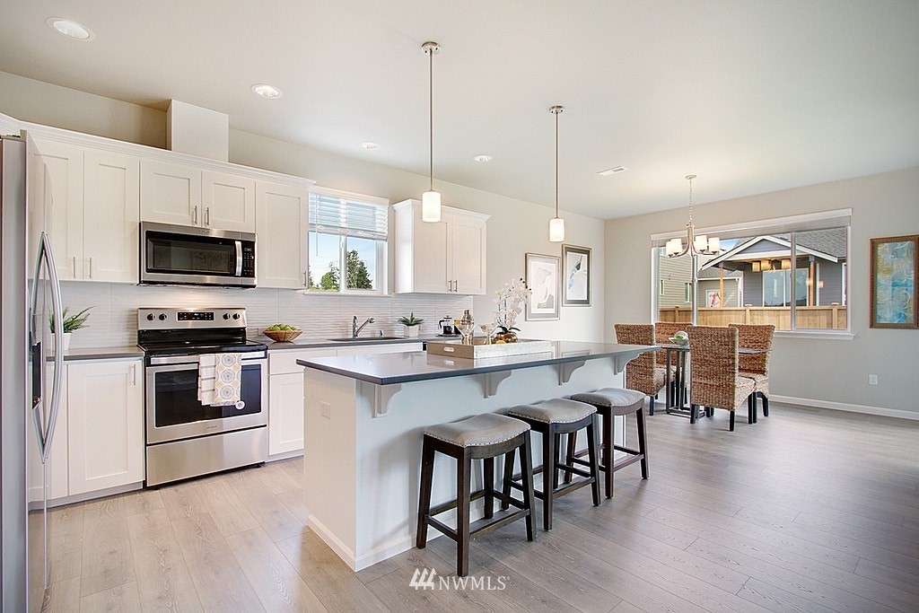 5202 Northeast 24th Street Renton, WA 98059 - Photo 7 of 22 a kitchen with stainless steel appliances granite countertop a stove a sink a microwave a dining table and chairs with wooden floor